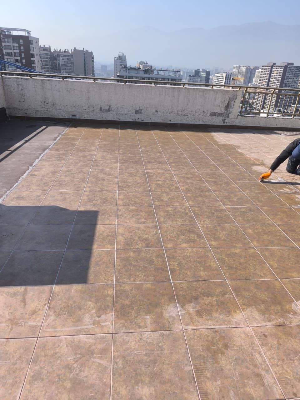 Aplicación de sello sobre el piso de una terraza en altura, con vista panorámica de Santiago